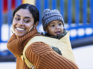 Mère qui porte son enfant dans un porte-bébé au dos