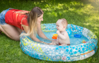 Bébé qui se baigne dans une piscine gonflable et sa mère le surveille 